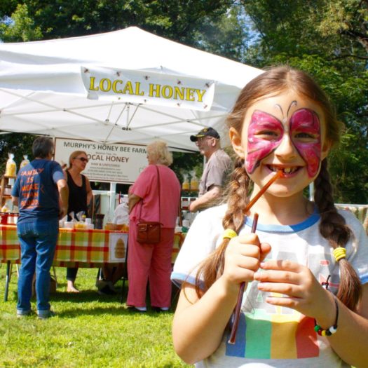 Young child eating a honey stick snack.