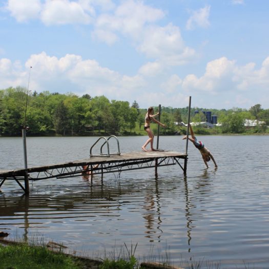 Children jumping off a boat dock into the lake.