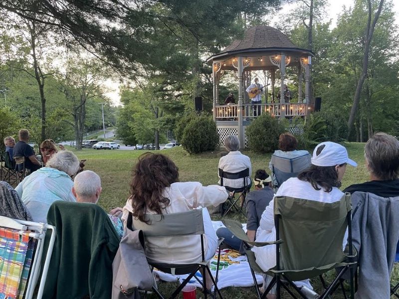 An audience watches an outdoor concert on Village Green