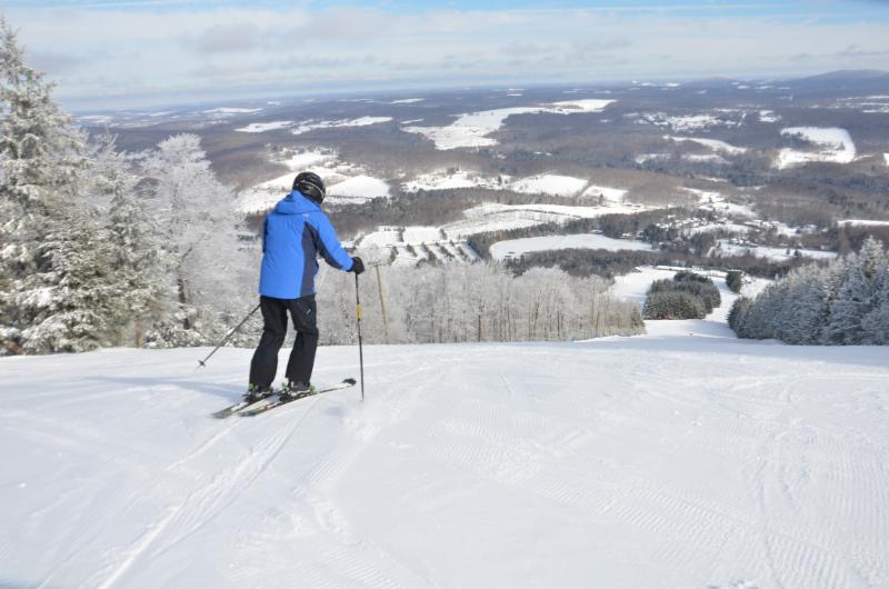 A skier stands at the top of the slopes at Elk Mountain with a view stretching miles into the distance