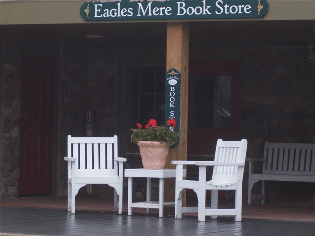 Two white wooden chairs in front of Eagles Mere Bookstore