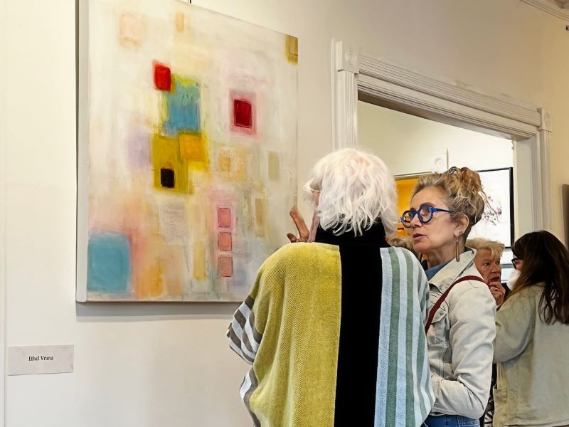 Two women look at an abstract painting at Pink Arrow Arts