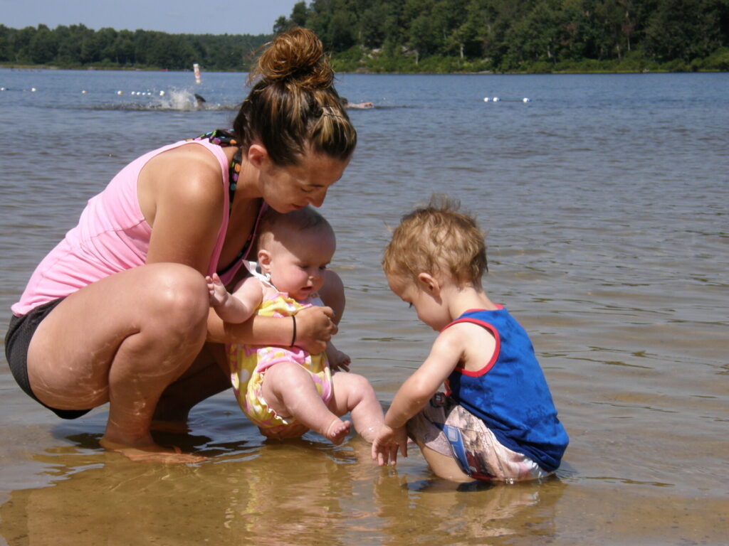 A woman and two babies play in the water at Lake Jean