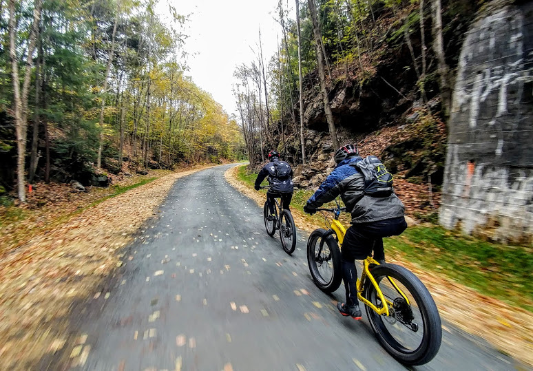 Two cyclists ride on the D&H Rail-Trail in autumn
