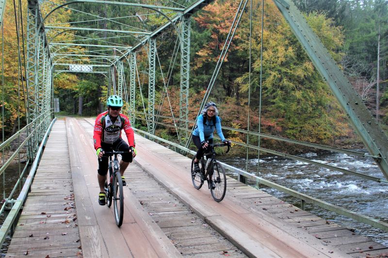 Two cyclists ride over a bridge over the Loyalsock Creek