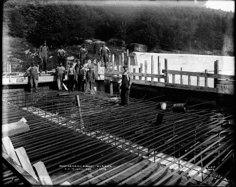 A black-and-white photo of workers standing on metal beams