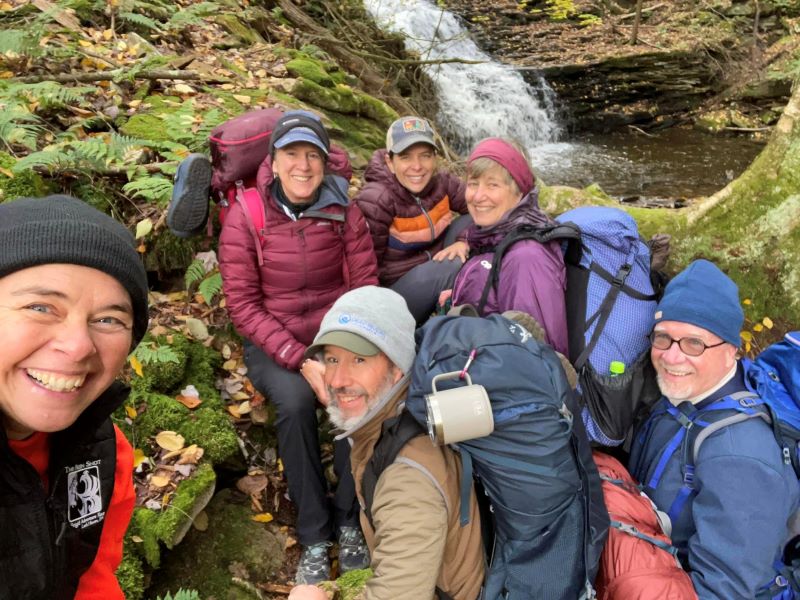 A group of hikers pose in front of a waterfall
