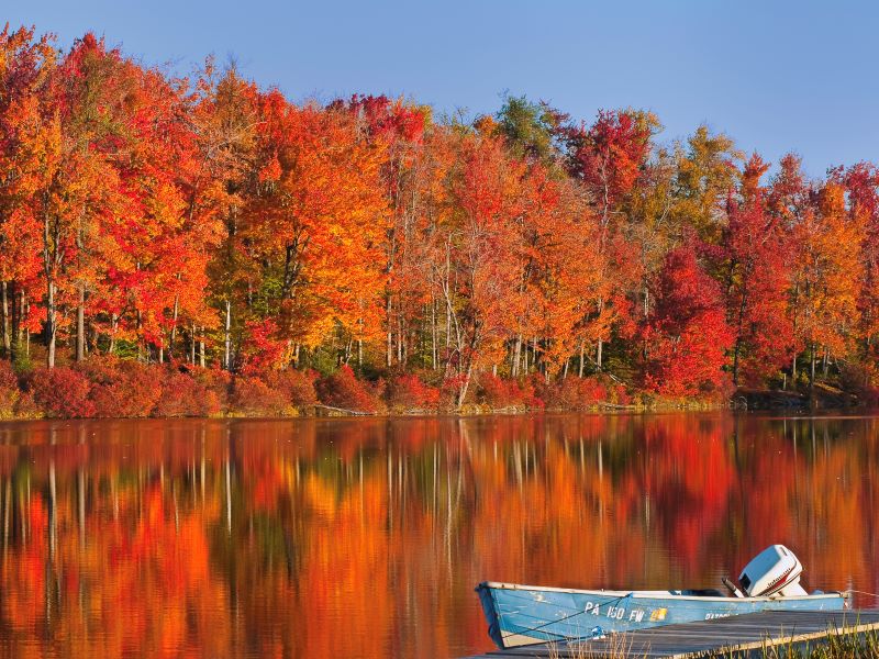A motorboat at Lake Jean with red fall foliage in the background