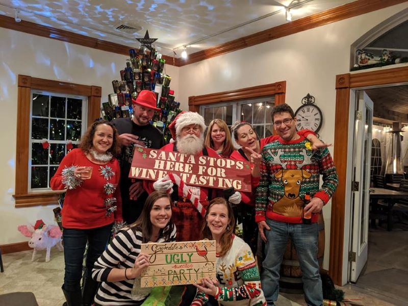 People wearing ugly sweaters and posing with Santa