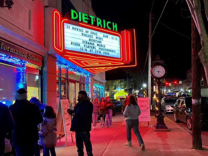 People walk beneath the neon marquee of the Dietrich Theater during Tunkhannock's Christmas in Our Hometown