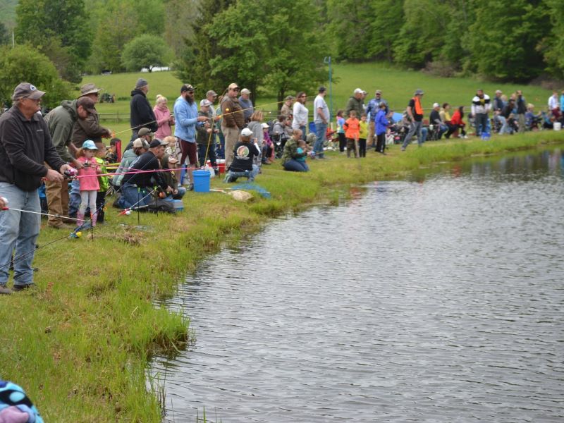 Children and their parents gather around the pond for the annual fishing derby