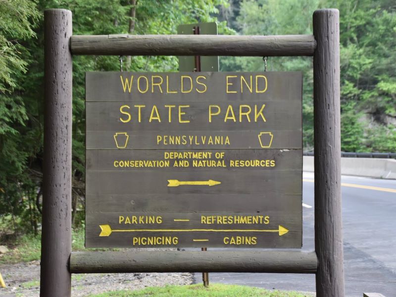 A brown sign with yellow text welcomes visitors to Worlds End