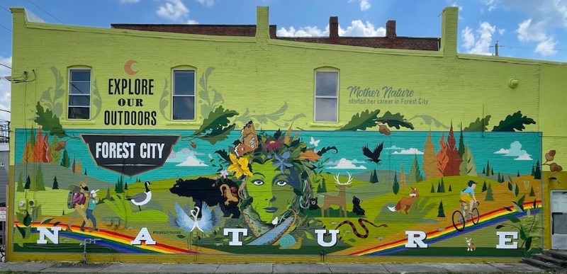 Mural featuring forest animals, Mother Nature, hikers, and cyclists.