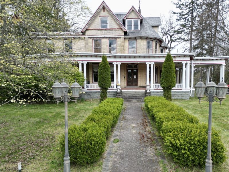 Queen Anne-style mansion with a yellow brick facade and wraparound porch.